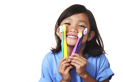 Photo of cavity-free happy young girl holding toothbrushes